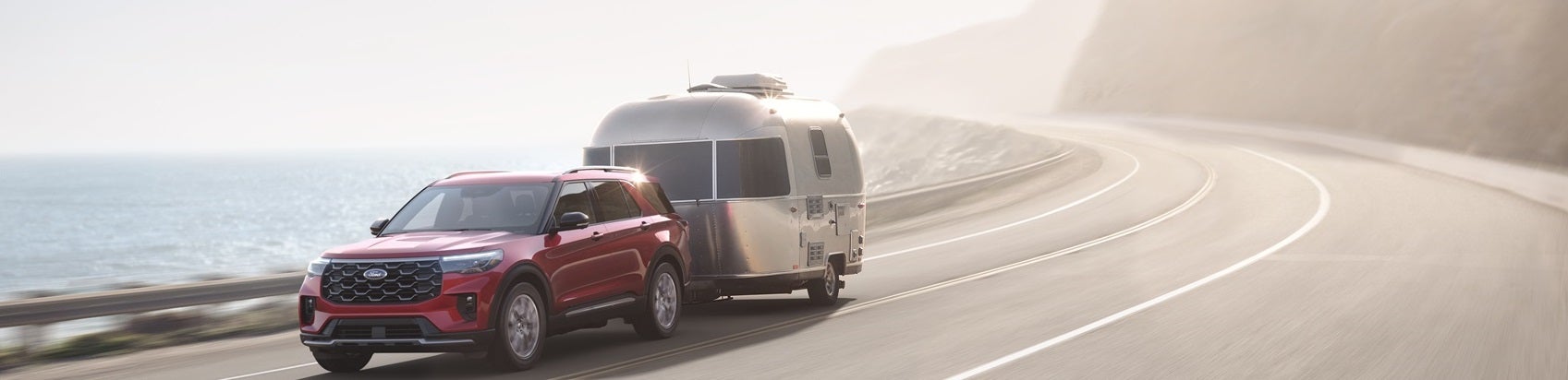 Ford Explorer hauling a camper on coastal highway